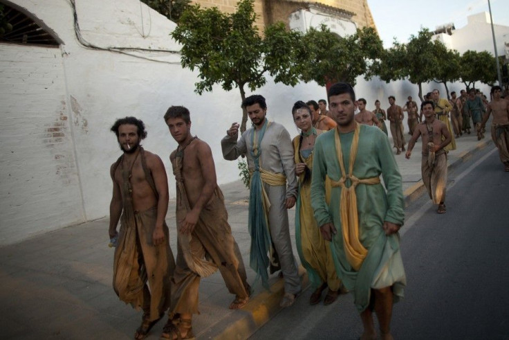 Extras walk along a street after taking part in the filming of the fifth season of the HBO TV series "Game of Thrones"
