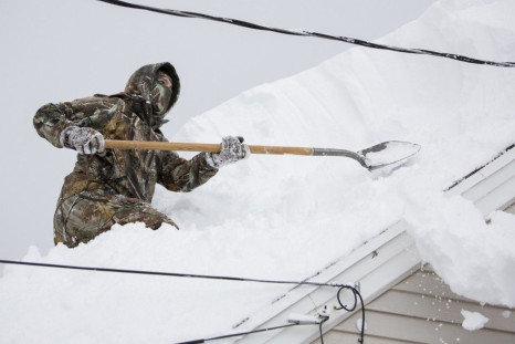 TJ Zydel works to clear his roof in the town of West Seneca near Buffalo, New York, November 20, 2014. Fresh snow fell on Thursday in snowbound western New York state, where longtime residents described the blast of winter weather as the worst in memory. 