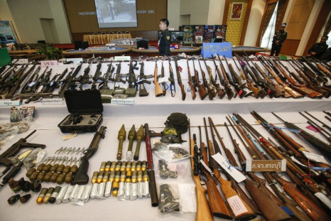 A soldier stands next to illegal weapons seized in raids following the May 22 military coup, during a news conference at a military barracks in Bangkok July 29, 2014. The weapons, ranging from shotguns to homemade bombs, and ammunition were seized during 