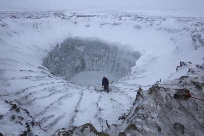 A member of an expedition group stands on the edge of a newly formed crater on the Yamal Peninsula, northern Siberia November 9, 2014. A group of scientists and discoverers in November went on an expedition initiated by the Russian Centre of Arctic Explor