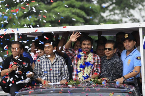 WBO welterweight champion Manny &quot;Pacman&quot; Pacquiao (C) waves during a victory parade in Manila November 27, 2014. The country's boxing hero Pacquiao outclassed American challenger Chris Algieri to retain his WBO welterweight title in Macau on Sun