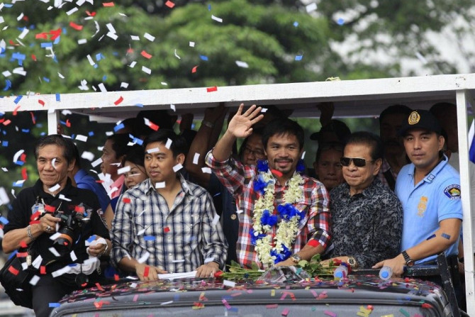 WBO welterweight champion Manny &quot;Pacman&quot; Pacquiao (C) waves during a victory parade in Manila November 27, 2014. The country's boxing hero Pacquiao outclassed American challenger Chris Algieri to retain his WBO welterweight title in Macau on Sun