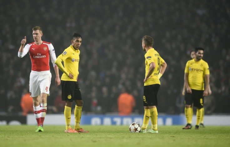 Arsenal's Per Mertesacker (L) gives a thumbs-up as Borussia Dortmund players stand dejected after a goal was scored during their Champions League group D soccer match in London November 26, 2014.