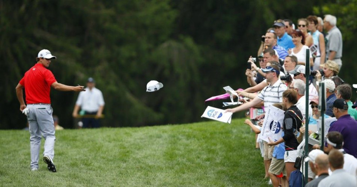 Australia&#039;s Adam Scott tosses a hat he autographed to the gallery as he walks on the 17th hole during a practice round for the 2013 PGA Championship golf tournament at Oak Hill Country Club in Rochester, New York August 7, 2013.