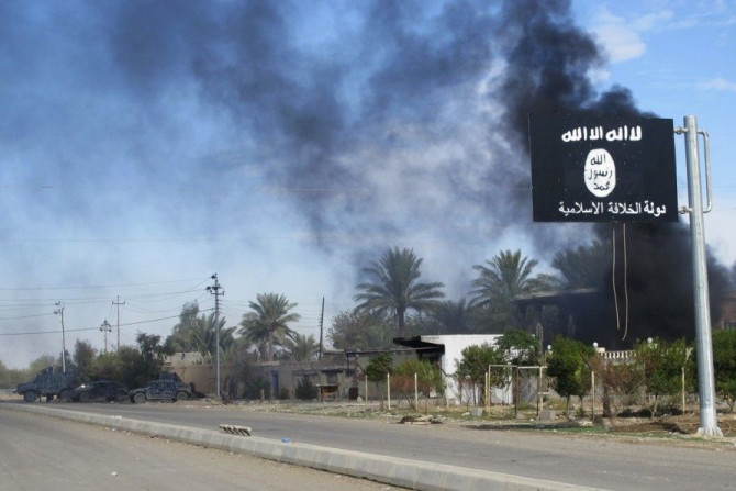 Smoke raises behind an Islamic State flag after Iraqi security forces and Shiite fighters took control of Saadiya in Diyala province from Islamist State militants, November 24, 2014.