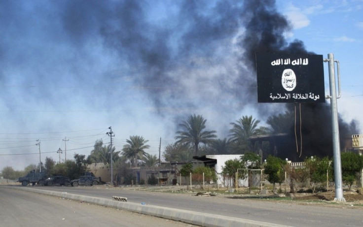 Smoke raises behind an Islamic State flag after Iraqi security forces and Shiite fighters took control of Saadiya in Diyala province from Islamist State militants, November 24, 2014.