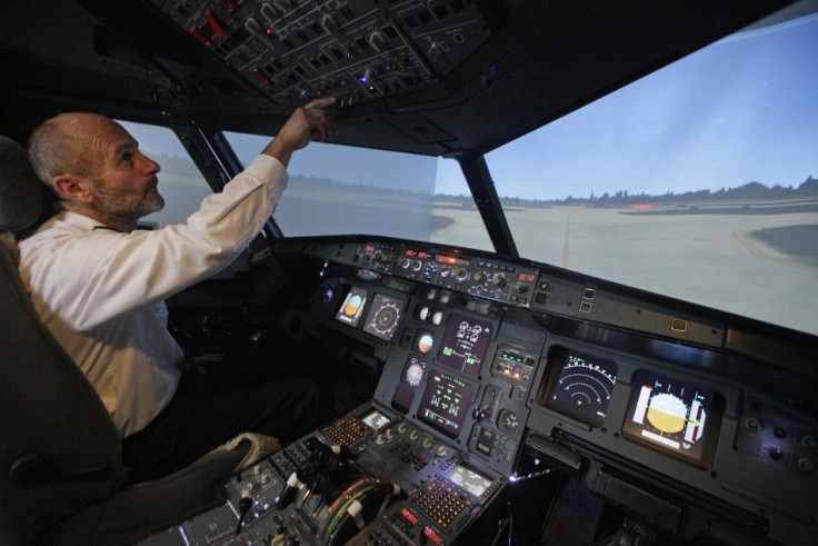 Perne (R) Checks The Controls Of A Flight Simulator