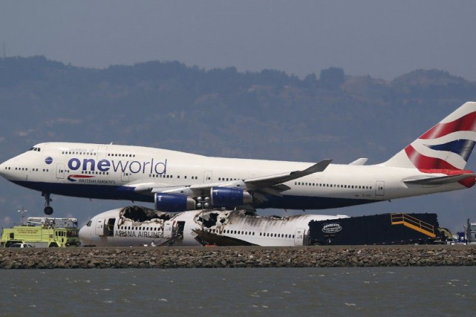 A British Airways Oneworld jumbo jet lands near the charred remains of Asiana Airlines Flight 214 on the runway at San Francisco Airport International Airport in San Francisco, California July 9, 2013.