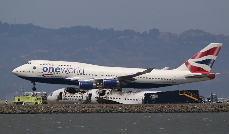 A British Airways Oneworld jumbo jet lands near the charred remains of Asiana Airlines Flight 214 on the runway at San Francisco Airport International Airport in San Francisco, California July 9, 2013.
