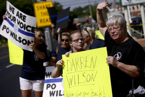 Demonstrators supporting Ferguson Police officer Darren Wilson hold signs during a rally in St. Louis, Missouri August 23, 2014.