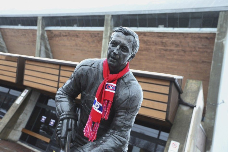 A view of a Jean Beliveau statue draped with a Montreal Canadiens scarf, is seen front of an arena named after Beliveau in Longueuil