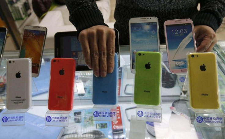 A clerk arranges Apple's iPhone 5C phones on racks bearing the logo of  China Mobile, at a mobile phone shop in Beijing December 23, 2013. Apple Inc  said it has signed a long-awaited agreement with China Mobile Ltd to sell iPhones through the world&