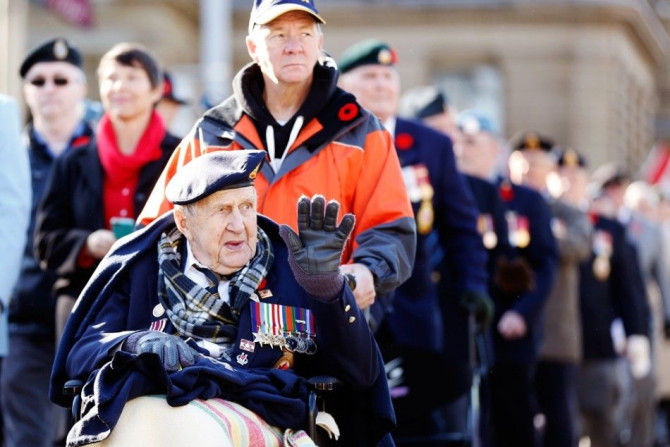 A veteran waves during a parade during Remembrance Day ceremonies at the National War Memorial in Ottawa