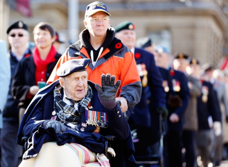 A veteran waves during a parade during Remembrance Day ceremonies at the National War Memorial in Ottawa