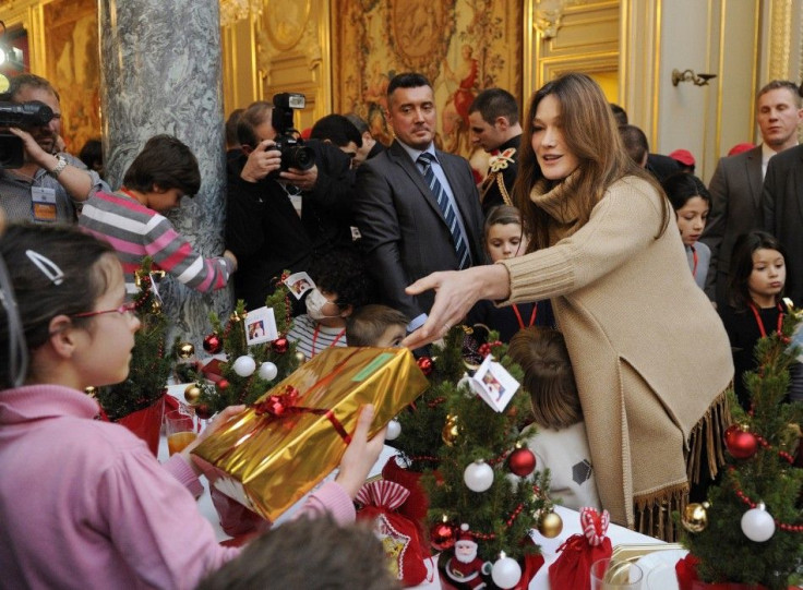 France&#039;s First Lady Carla Bruni-Sarkozy (R) gives gifts to children of Alsace during the Christmas party at the Elysee Palace in Paris December 14, 2011.