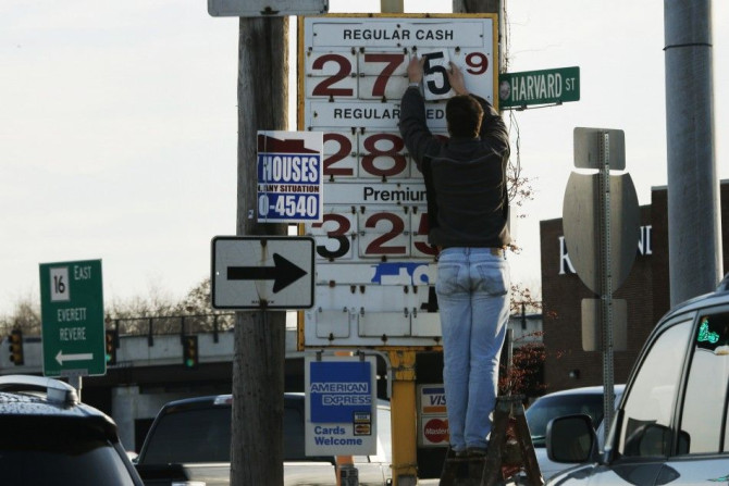A man changes the price for a gallon of gasoline at a gas station