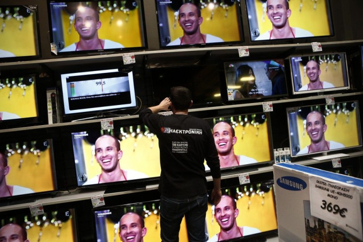 Employee of Electroniki retail chain Yannis Papageorgiou sets a television at an Electroniki shop in Athens November 27, 2014. Greece has muddled through 20 consecutive months of deflation, or continuously falling consumer prices ? a phenomenon that econo