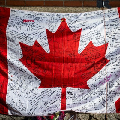 Messages are seen on a Canadian flag in a makeshift memorial in honour of Cpl. Nathan Cirillo