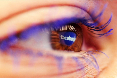 A Facebook logo reflected in the eye of a woman