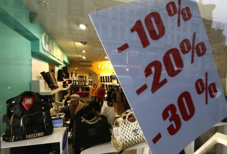 Customers visit a shop with a sale advertisement displayed on its window in St. Petersburg