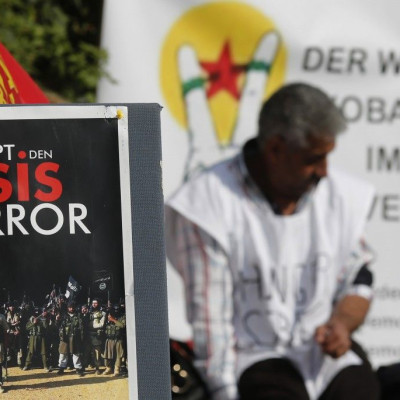 A Kurdish protester sits behind a sign reading &quot; STOP ISIS terror&quot; in front of the United Nations headquarters in Vienna October 9, 2014. A group of Kurdish people living in Austria are on hunger strike since Monday in solidarity for Syrian Kurd