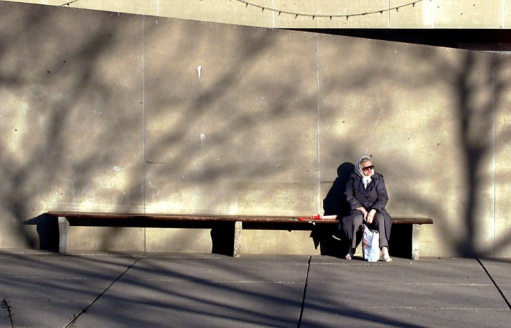 An elderly women sits in the warm sun surrounded by the shadows of winter outside Toronto City Hall