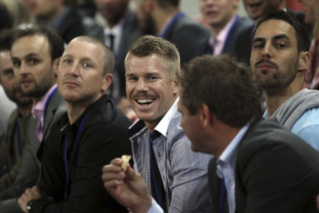 Australian cricketer David Warner (C) smiles while watching the international rugby union match between Australia and France at Suncorp Stadium in Brisbane June 7, 2014.