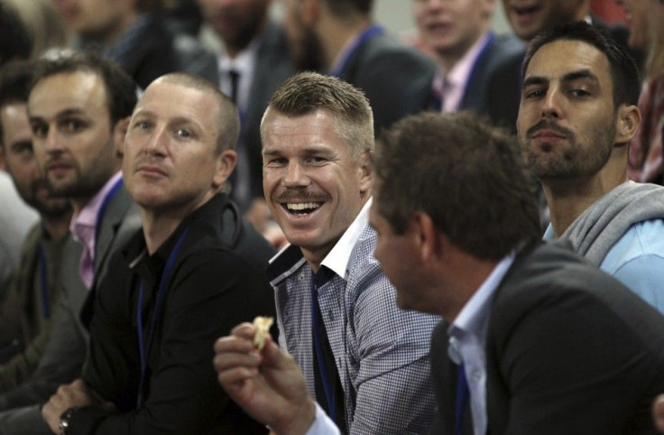 Australian cricketer David Warner (C) smiles while watching the international rugby union match between Australia and France at Suncorp Stadium in Brisbane June 7, 2014.