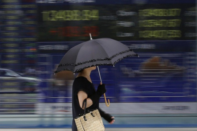 A woman walks past a stock quotation board outside a brokerage in Tokyo September 2, 2013. Asian shares climbed to a two-week high on Monday, and the Australian dollar and copper gained, as China said its manufacturing expanded in August at the fastest pa