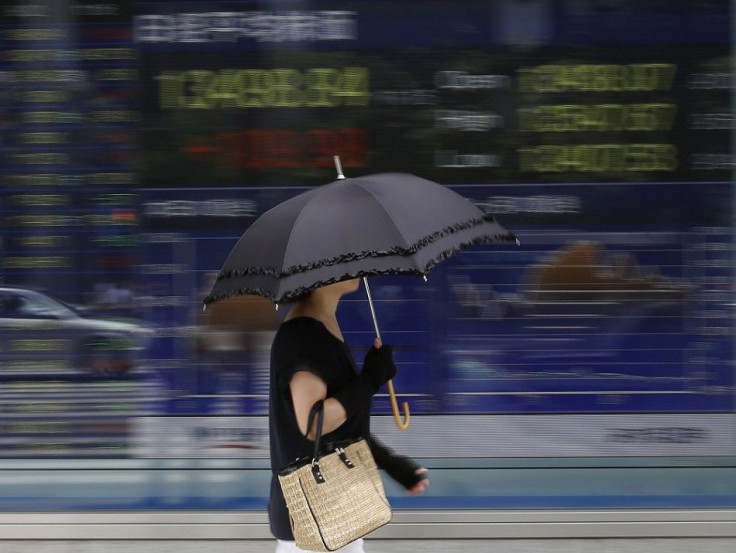 A woman walks past a stock quotation board outside a brokerage in Tokyo September 2, 2013. Asian shares climbed to a two-week high on Monday, and the Australian dollar and copper gained, as China said its manufacturing expanded in August at the fastest pa