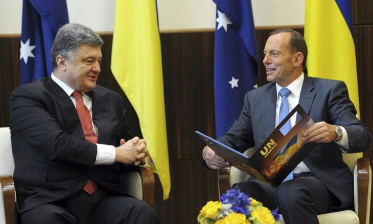 Australia's Prime Minister Tony Abbott (R) talks with Ukraine's President Petro Poroshenko after the latter presented him with a book, during their meeting in Melbourne December 11, 2014. Poroshenko is on a three-day official visit to Australia from Decem