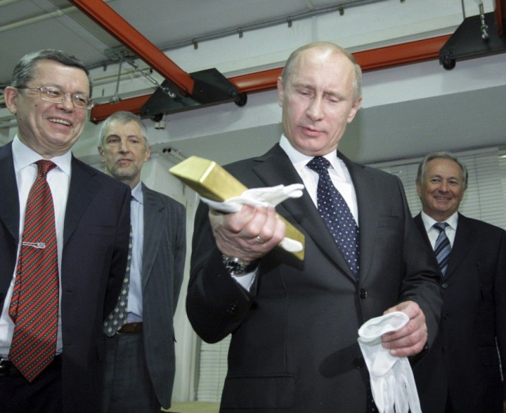 Russia's Prime Minister Vladimir Putin (2nd R) holds an ingot of gold as he visits the precious metals safe vault of the Central Bank in Moscow January 24, 2011. REUTERS/Alexsey Druginyn/RIA Novosti/Pool