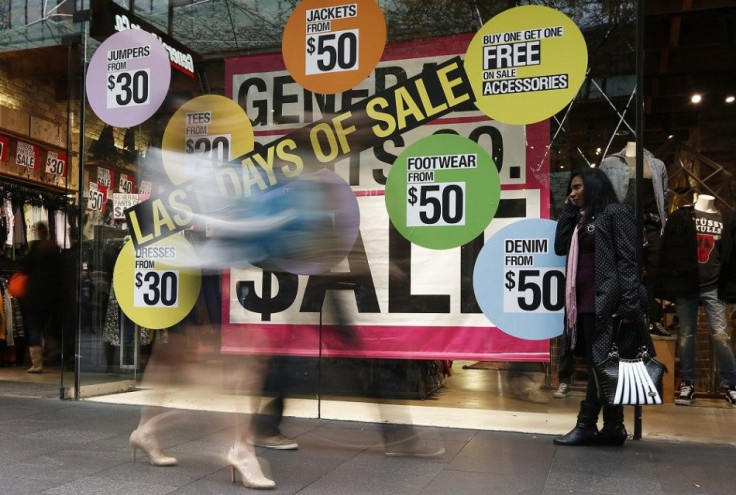 A woman uses her mobile phone in front of sale signs in the window of a clothes store at a shopping mall in central Sydney June 6, 2013. Australia's economy posted a second straight quarter of moderate growth as a drop in business investment offset gains 