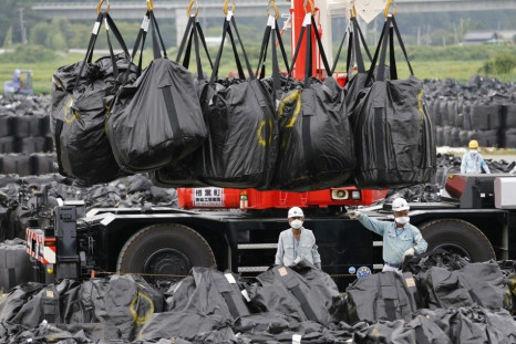 Workers move waste containing radiated soil, leaves and debris from the decontamination operation at a storage site in Naraha town, which is inside the formerly no-go zone of a 20 km (12 mile) radius around the crippled Fukushima Daiichi nuclear power pla