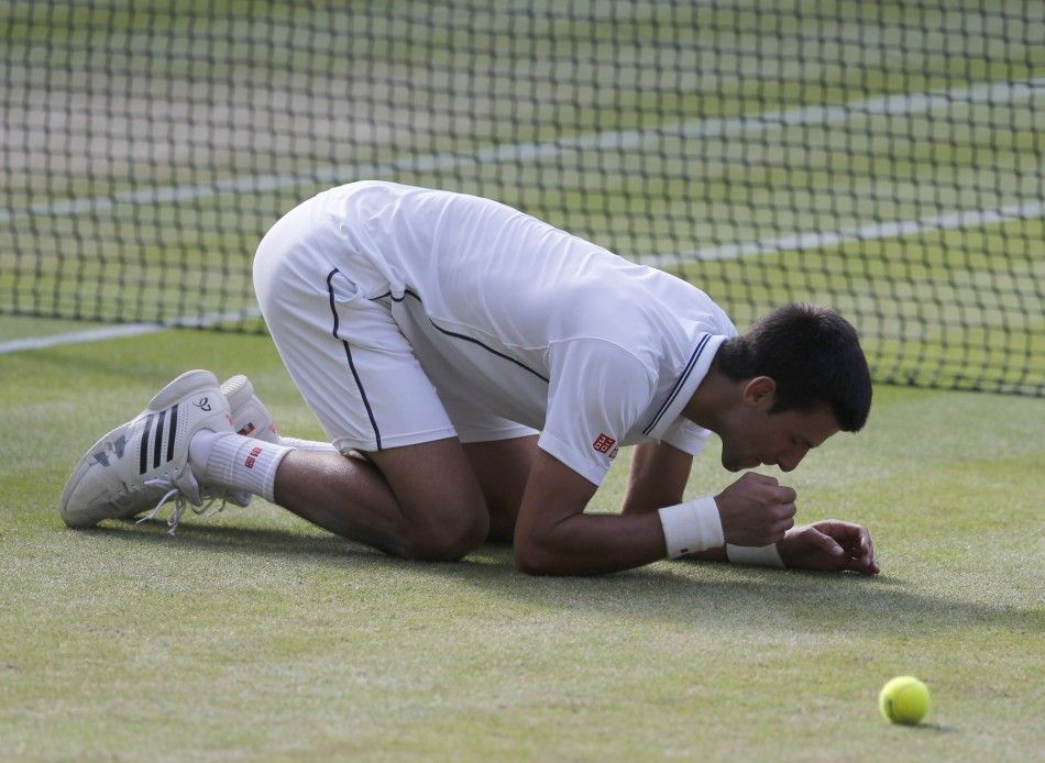 Novak Djokovic of Serbia eats some grass after defeating Roger Federer of Switzerland in their mens singles final tennis match at the Wimbledon Tennis Championships, in London July 6, 2014. 