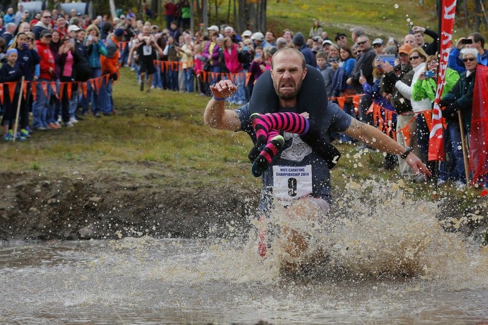 Eventual winners Jesse Wall carries Christina Arsenault through the water pit while competing in the North American Wife Carrying Championship at Sunday River ski resort in Newry, Maine October 11, 2014. 