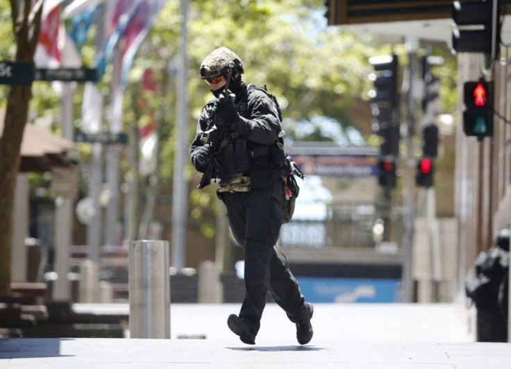 A police officer runs across Martin Place near Lindt Cafe where hostages are being held, in central Sydney December 15, 2014. Dozens of hostages were trapped inside the central Sydney cafe on Monday, with local television showing some being forced to hold