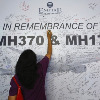 A woman writes a message on a dedication board for the victims of the downed Malaysia Airlines Flight MH17 airliner and the missing Flight MH370, in Subang Jaya outside Kuala Lumpur July 23, 2014. All sides in Ukraine&#039;s civil war must protect civilia