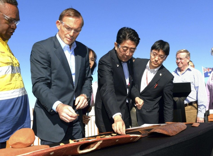 Japanese Prime Minister Shinzo Abe (C) and Australian Prime Minister Tony Abbott (2nd L) examine boomerangs during a tour of the Rio Tinto West Angelas iron ore mine