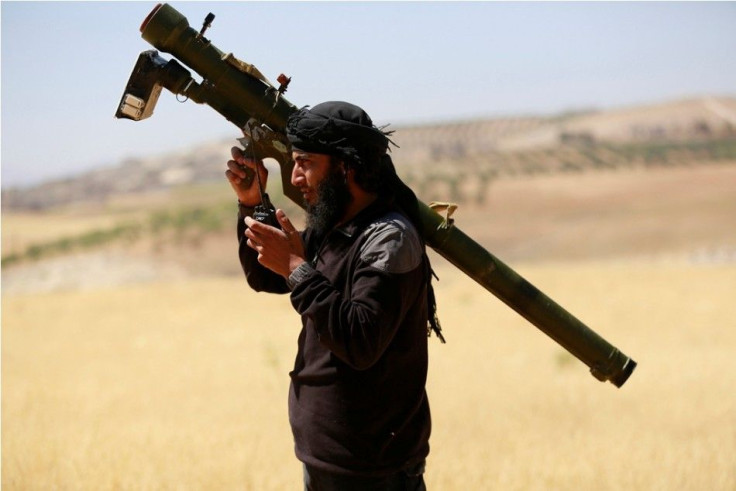 An Islamist Syrian rebel group Jabhat al-Nusra fighter talks on a walkie-talkie while carrying his weapon on Al-Khazan frontline of Khan Sheikhoun