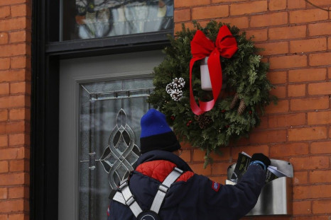 A Canada Post employee delivers mail in Ottawa December 11, 2013. Canada's postal service will phase out urban home delivery within five years and hike the cost of postage stamps to try to stem soaring losses, the post office said on Wednesday. REUTE