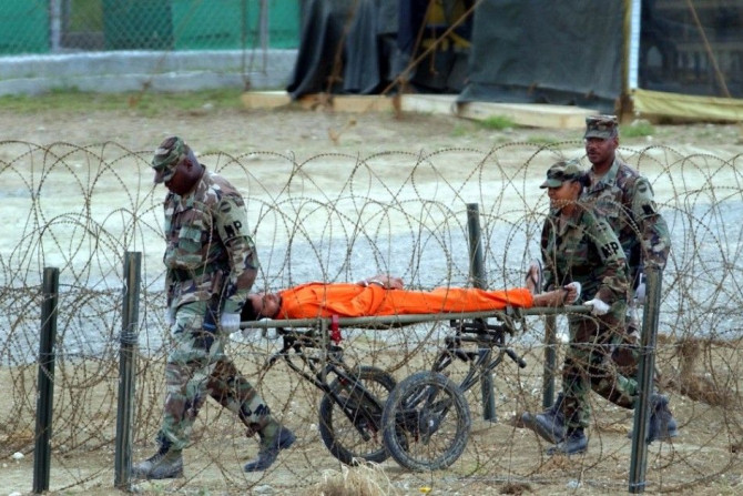A detainee is carried by military police after being interrogated by officials at Camp X-Ray at the U.S. Naval Base at Guantanamo Bay, Cuba, Wednesday, Feb. 6, 2002.