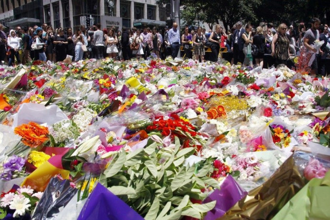 Members of the public look at floral tributes placed near the cafe where hostages were held for over 16-hours, in central Sydney December 16, 2014. Heavily armed Australian police stormed a Sydney cafe early on Tuesday morning and freed terrified hostages