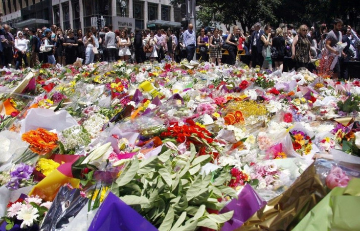 Members of the public look at floral tributes placed near the cafe where hostages were held for over 16-hours, in central Sydney December 16, 2014. Heavily armed Australian police stormed a Sydney cafe early on Tuesday morning and freed terrified hostages