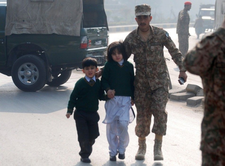 A Soldier Escorts Schoolchildren From The Army Public School Under Attack By Taliban Gunmen In Peshawar
