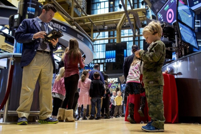 Jordan Kessler, (R ) son of trader Glenn Kessler, (L) uses his father's mobile phone and badge on the floor of the New York Stock Exchange November 28, 2014. Traders traditionally bring their children to work for the half day of trading on the Friday afte