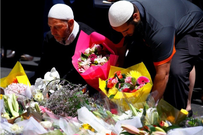 Members of the Australian Muslim community place floral tributes amongst thousands of others near the Lindt cafe