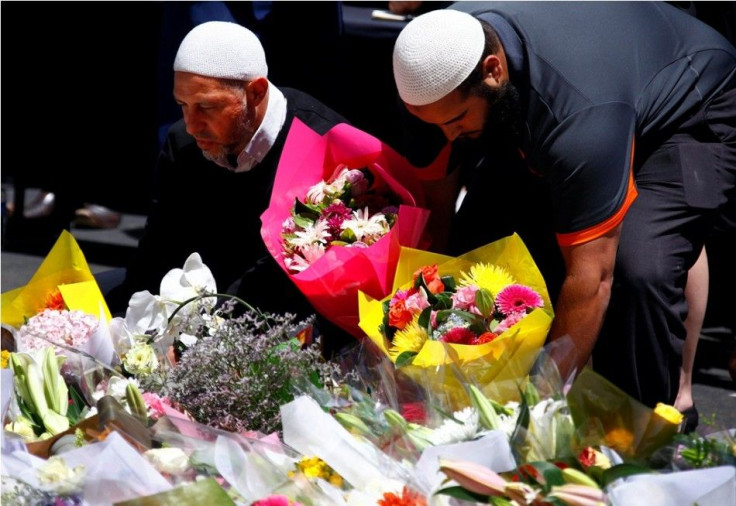 Members of the Australian Muslim community place floral tributes amongst thousands of others near the Lindt cafe