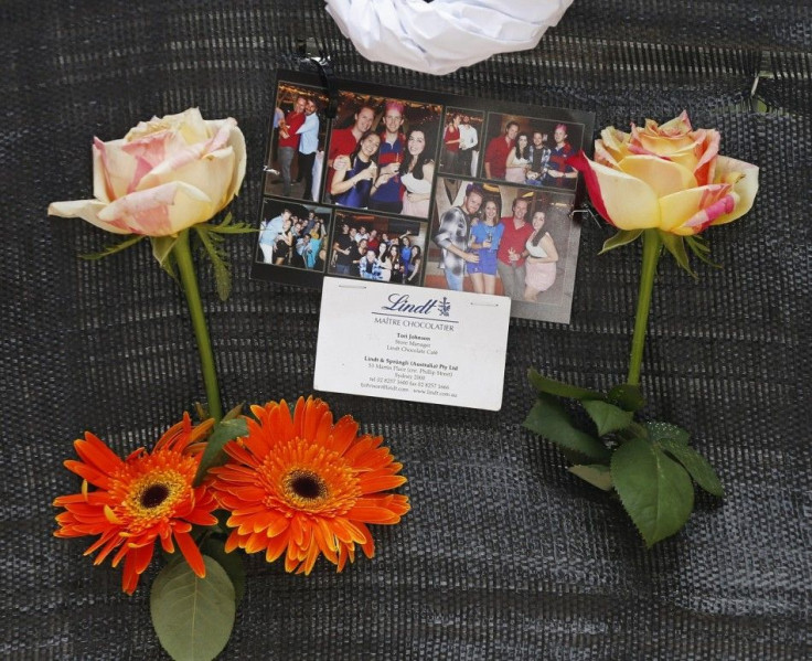 A business card bearing the name of Sydney siege victim, Lindt Cafe store manager Tori Johnson, is pictured among photos of him wearing a red shirt at an impromptu memorial in Martin Place December 17, 2014. Tough new national security laws failed to prev