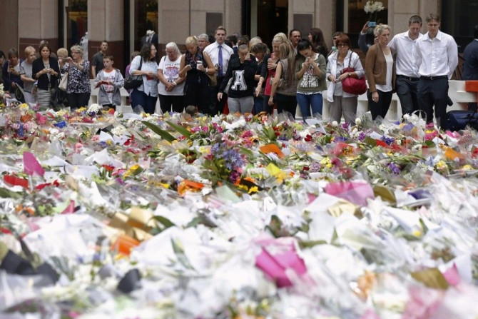 Three unidentified relatives (3rd R-R) of Sydney cafe siege victim, lawyer Katrina Dawson, gather after laying a floral tribute to her in Martin Place December 18, 2014. Australian Prime Minister Tony Abbott on Wednesday ordered a sweeping investigation i